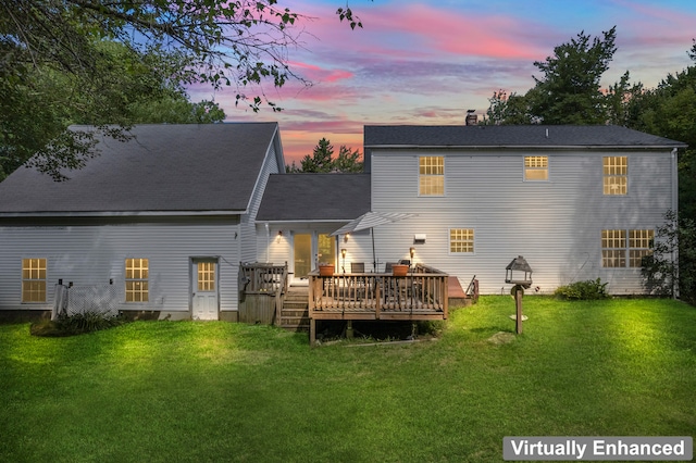 back house at dusk with a wooden deck and a yard