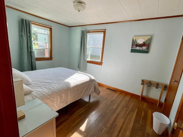 bedroom with ornamental molding, dark wood-type flooring, and multiple windows