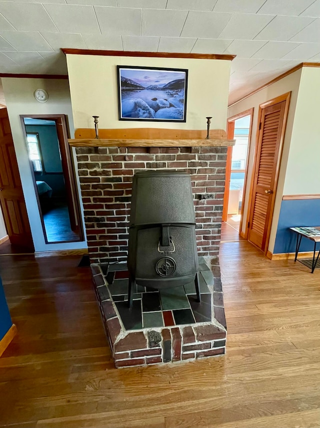 interior details featuring ornamental molding, hardwood / wood-style floors, and a wood stove