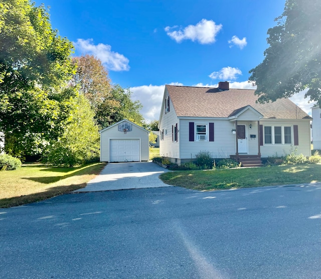 view of front of home with a front yard, a garage, and an outbuilding