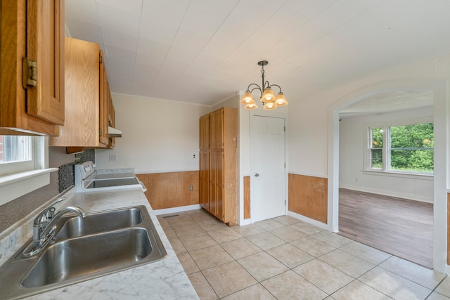 kitchen with a chandelier, sink, range, wood walls, and light tile patterned floors