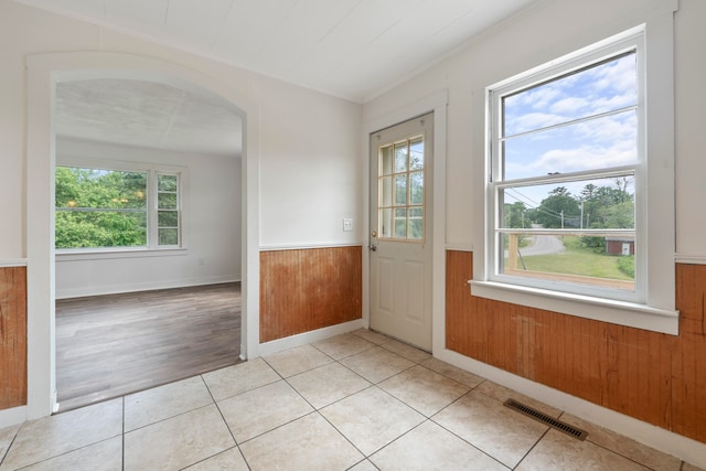 doorway featuring a healthy amount of sunlight, wooden walls, and light hardwood / wood-style flooring