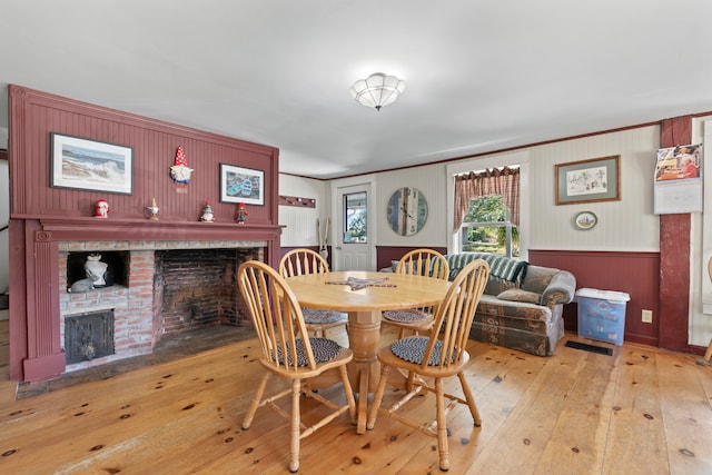 dining area with a brick fireplace and light wood-type flooring