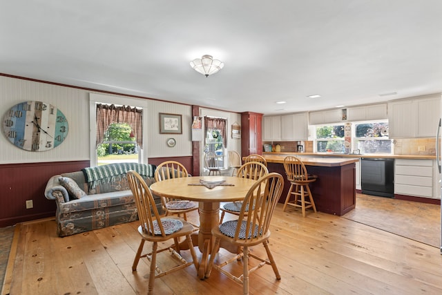 dining space with light wood-type flooring, wood walls, and a wealth of natural light