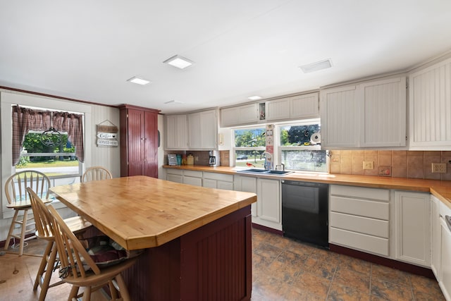 kitchen featuring decorative backsplash, black dishwasher, and sink