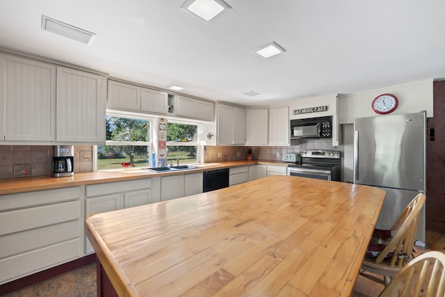 kitchen with backsplash, butcher block counters, sink, and black appliances