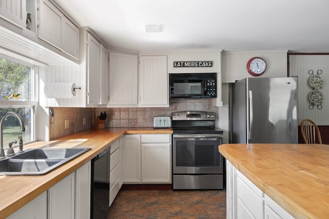 kitchen with butcher block counters, sink, white cabinetry, and black appliances