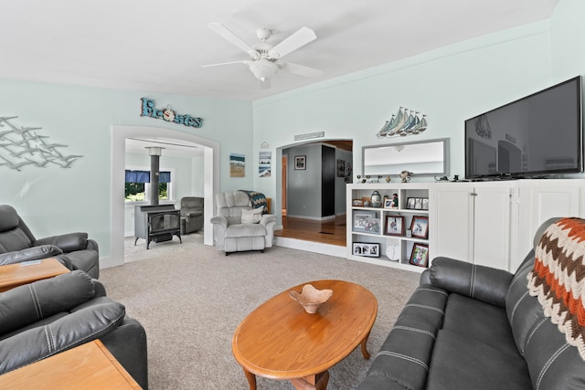 living room featuring ceiling fan, light colored carpet, lofted ceiling, and a wood stove