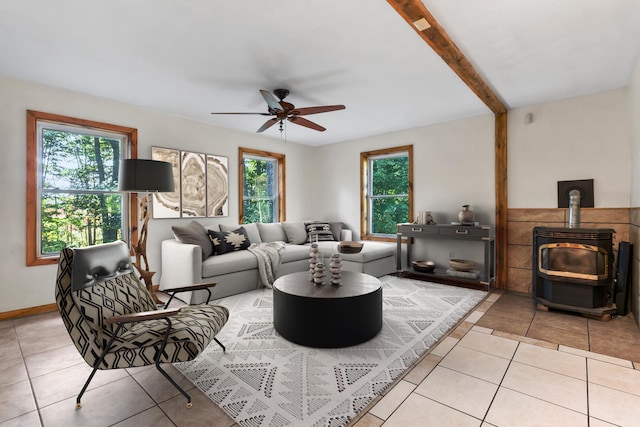 tiled living room featuring a healthy amount of sunlight, beam ceiling, ceiling fan, and a wood stove