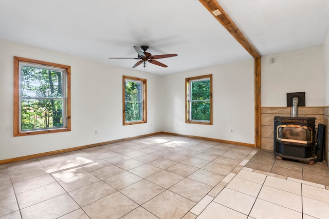 unfurnished living room with ceiling fan, beamed ceiling, light tile patterned floors, and a wood stove