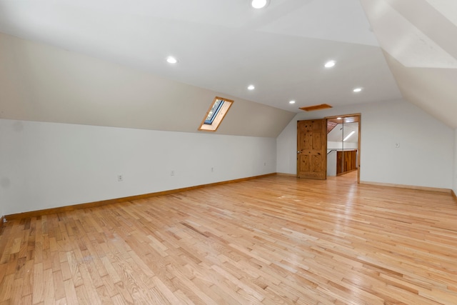 additional living space with light wood-type flooring and lofted ceiling with skylight