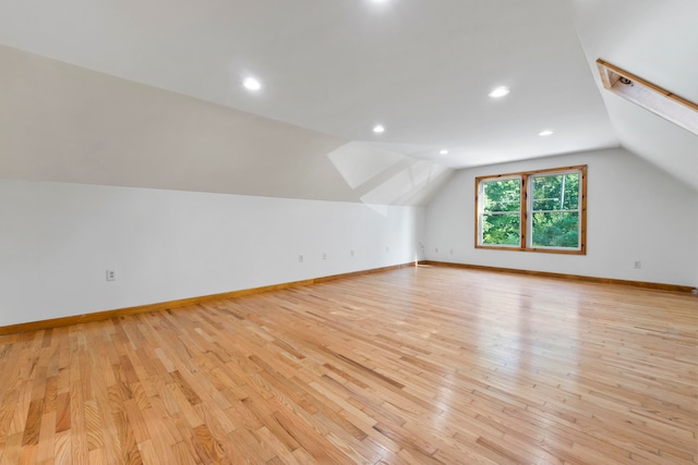 bonus room with light wood-type flooring and vaulted ceiling