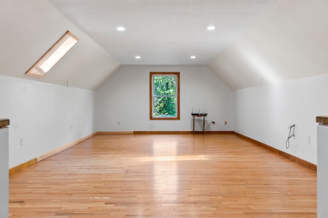 bonus room featuring light wood-type flooring and vaulted ceiling with skylight