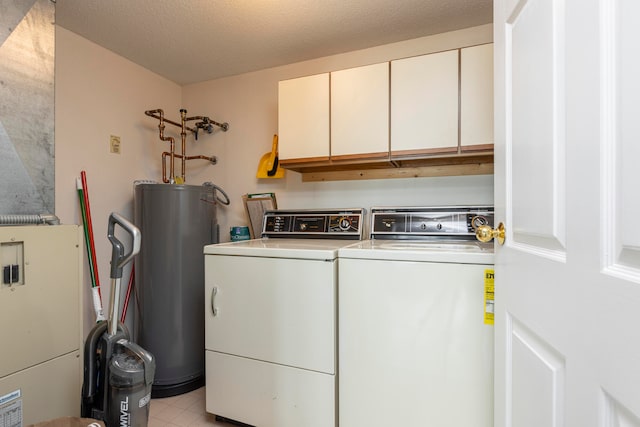 clothes washing area featuring a textured ceiling, water heater, washing machine and dryer, and cabinets