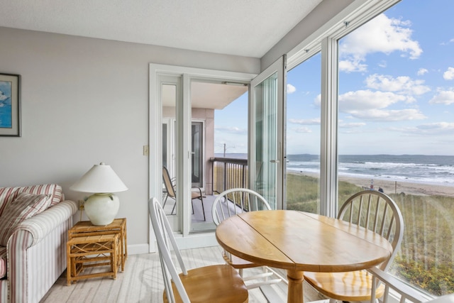 dining room featuring a view of the beach, a water view, and light hardwood / wood-style flooring