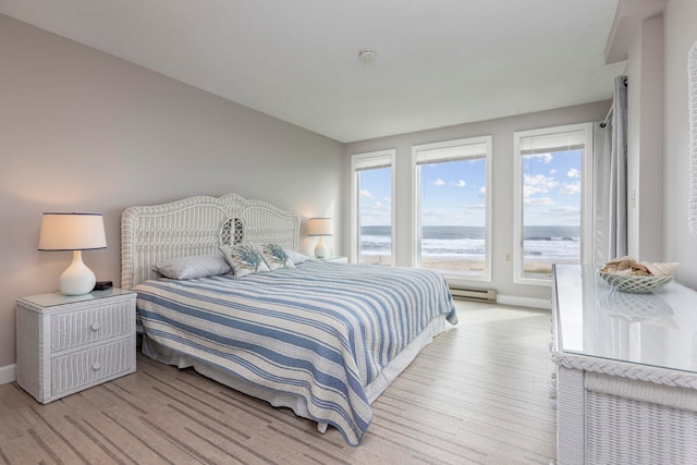 bedroom featuring a water view, light hardwood / wood-style floors, multiple windows, and a baseboard radiator