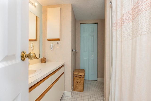 bathroom with a textured ceiling, tile patterned flooring, and vanity