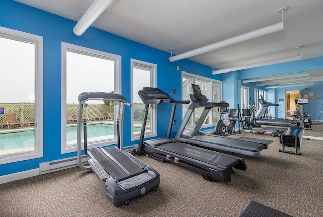 workout area featuring a textured ceiling, a baseboard radiator, and carpet flooring