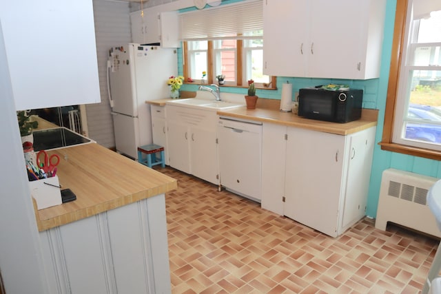 kitchen with radiator, sink, white appliances, backsplash, and white cabinetry