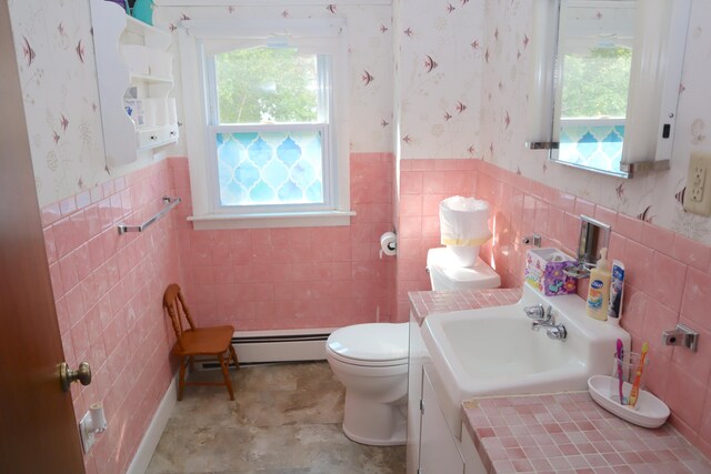 bathroom with baseboard heating, tile walls, vanity, and toilet