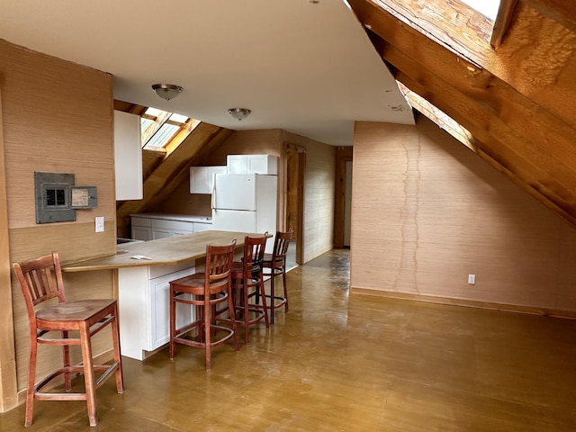 kitchen with a kitchen breakfast bar, wood walls, kitchen peninsula, and white fridge