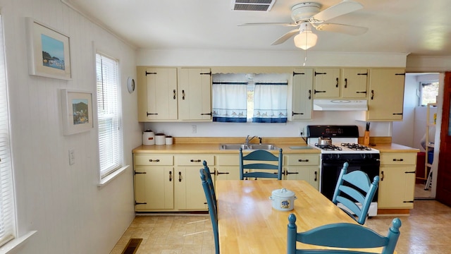 kitchen featuring ceiling fan, cream cabinets, range with gas stovetop, and sink