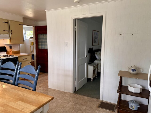 kitchen with gas stove, crown molding, and wooden walls