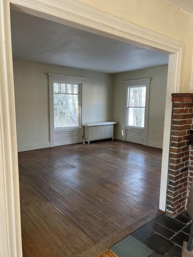 unfurnished living room featuring radiator heating unit and dark hardwood / wood-style flooring