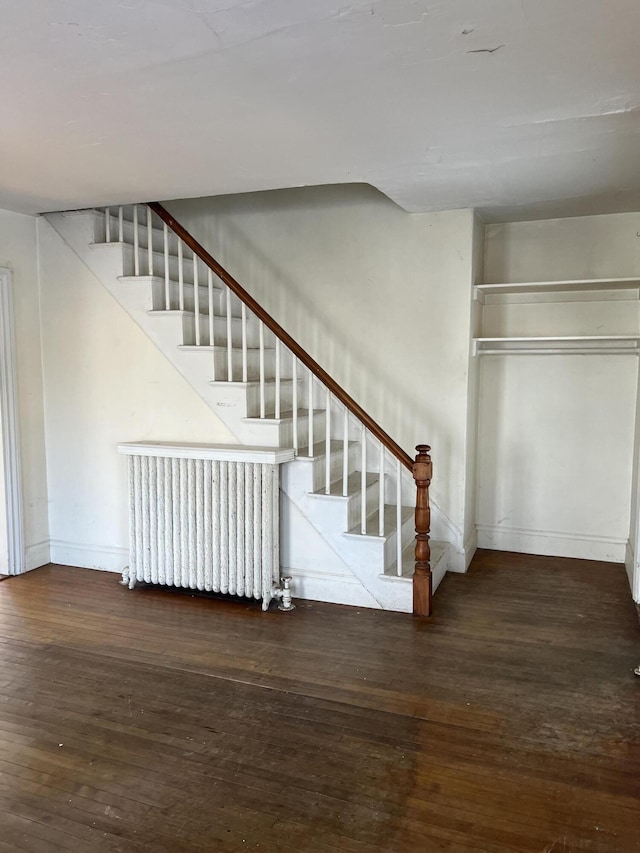 stairway featuring radiator heating unit and wood-type flooring