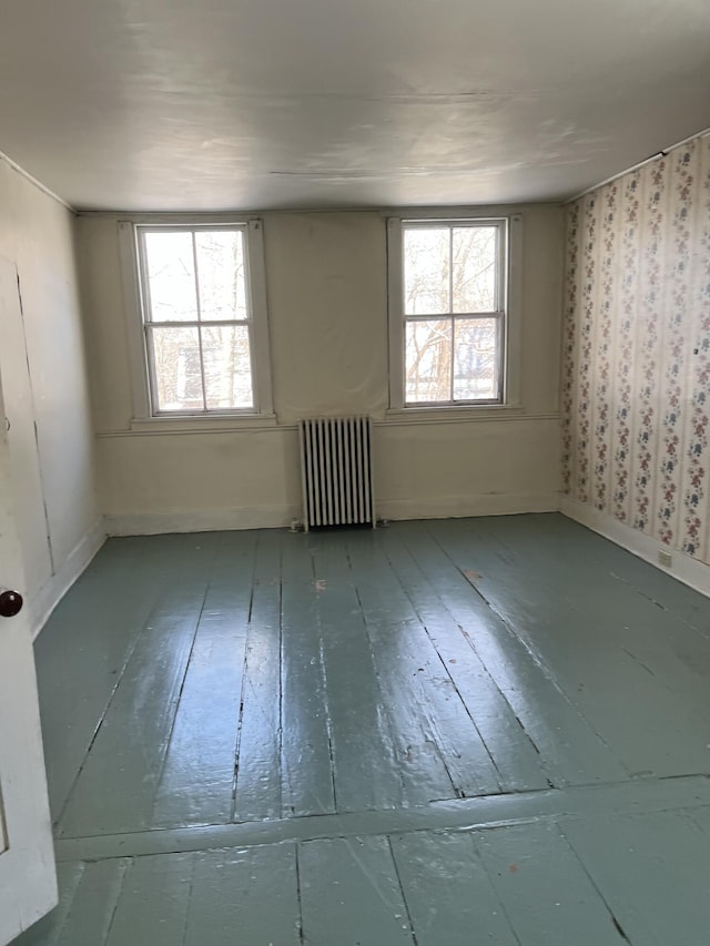 spare room with radiator, hardwood / wood-style flooring, and plenty of natural light