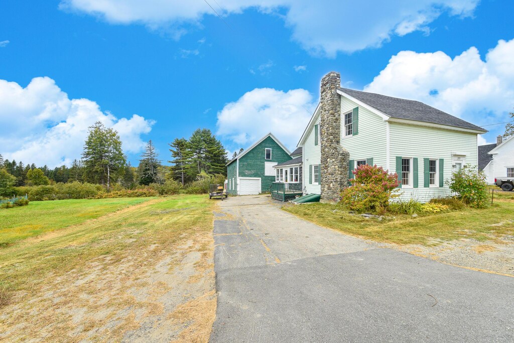 704 Main St, Moose River, ME 04945 - view of side of home featuring aphalt driveway, a chimney, a garage, a lawn, and an outdoor structure