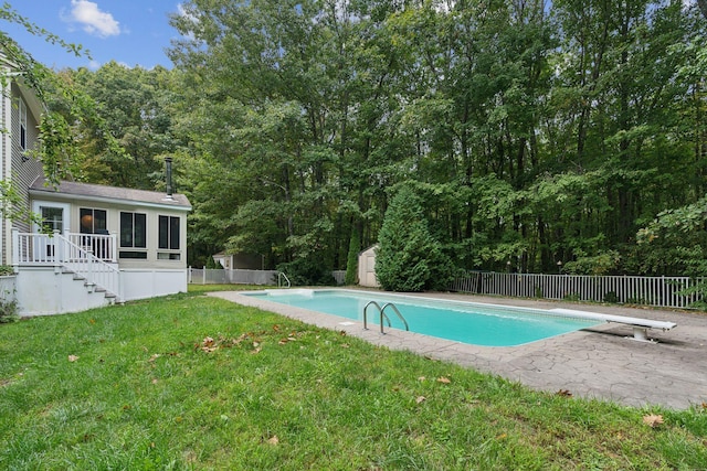 view of swimming pool with a storage shed, a lawn, and a diving board