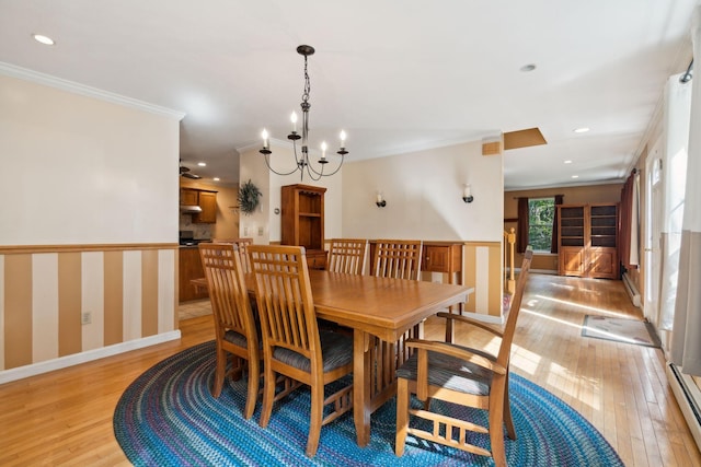 dining space featuring light hardwood / wood-style flooring, a baseboard heating unit, a chandelier, and ornamental molding