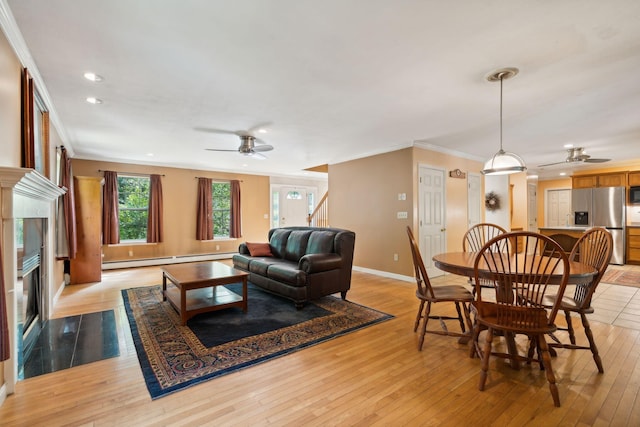 living room with light hardwood / wood-style floors, a premium fireplace, ceiling fan, and crown molding