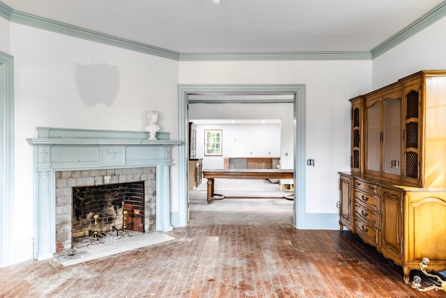 living area with a fireplace with flush hearth, crown molding, wood finished floors, and baseboards