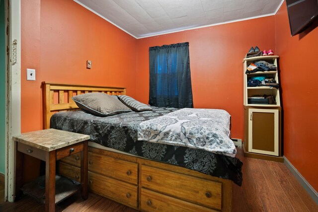 bedroom with dark wood-type flooring and crown molding