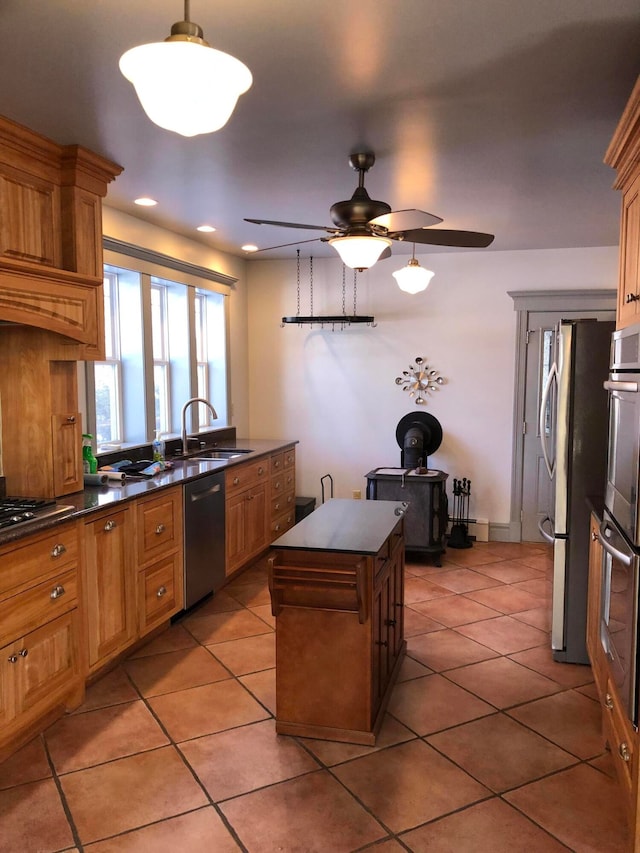 kitchen with ceiling fan, light tile patterned floors, sink, stainless steel appliances, and a center island