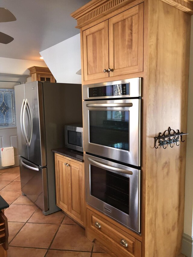 kitchen with light tile patterned flooring, ceiling fan, and stainless steel appliances