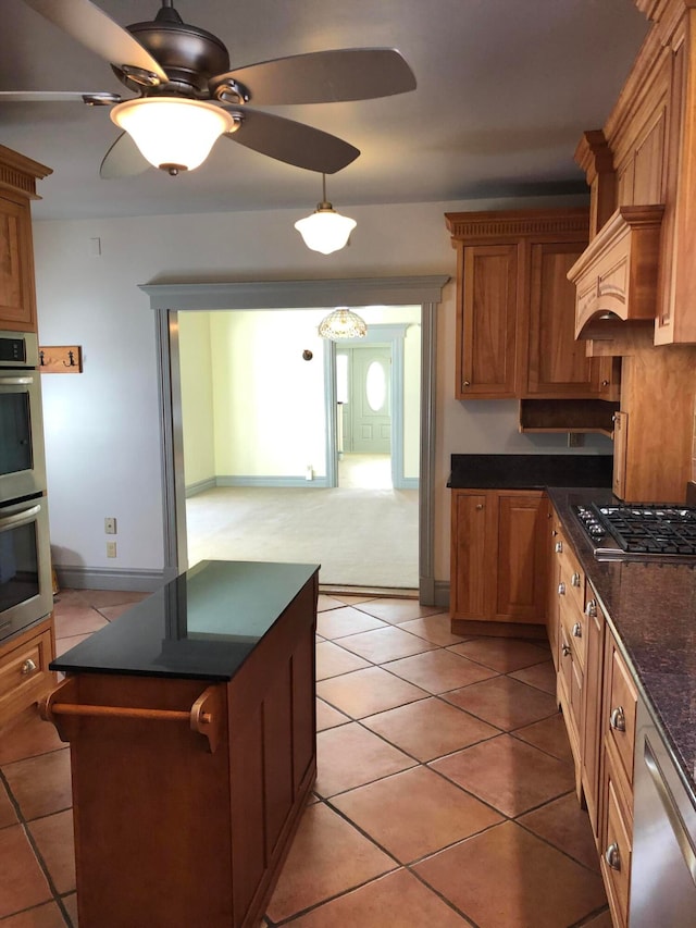 kitchen with appliances with stainless steel finishes, light tile patterned flooring, and ceiling fan