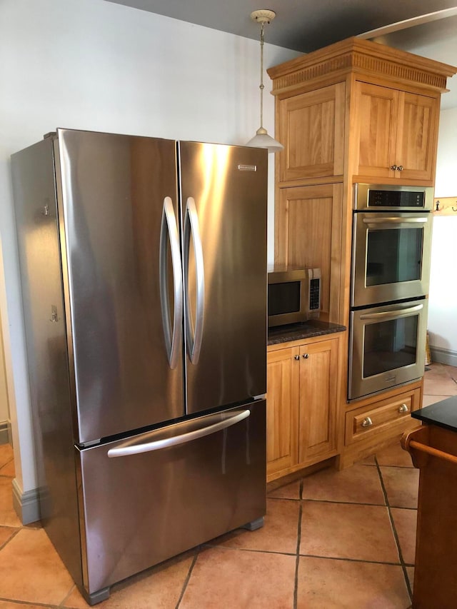 kitchen with appliances with stainless steel finishes, hanging light fixtures, and light tile patterned floors