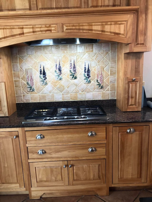 interior space featuring dark stone counters, tile patterned floors, tasteful backsplash, and gas cooktop