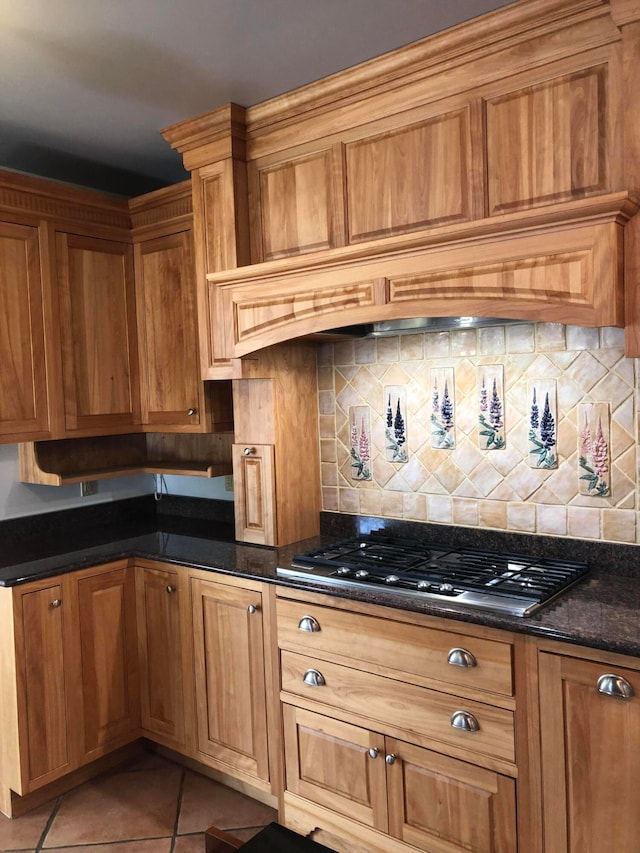 kitchen featuring dark stone counters, light tile patterned flooring, decorative backsplash, and black gas cooktop