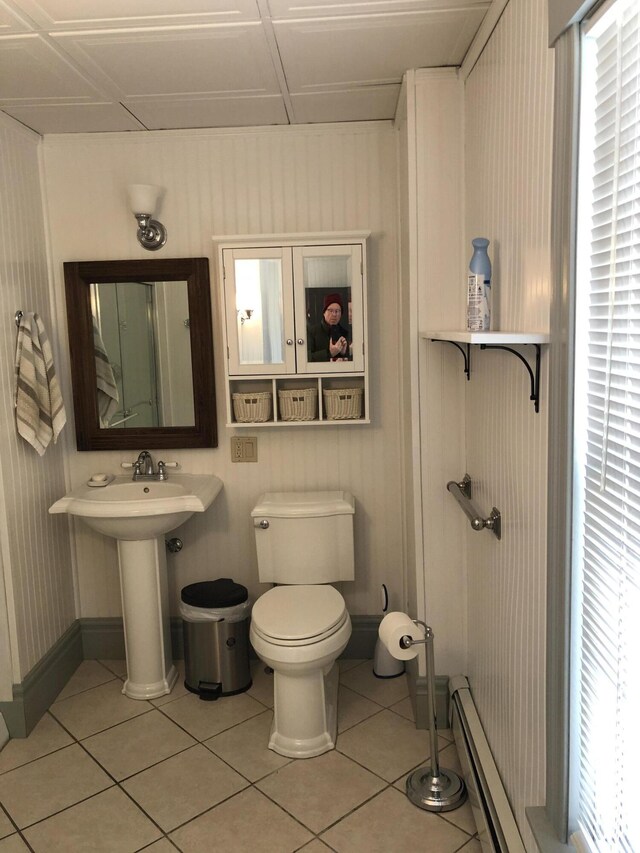 bathroom with a baseboard radiator, a wealth of natural light, tile patterned floors, and toilet