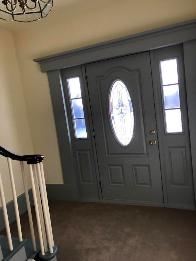 foyer entrance featuring an inviting chandelier and carpet floors