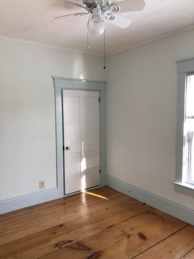 empty room featuring wood-type flooring, crown molding, ceiling fan, and plenty of natural light