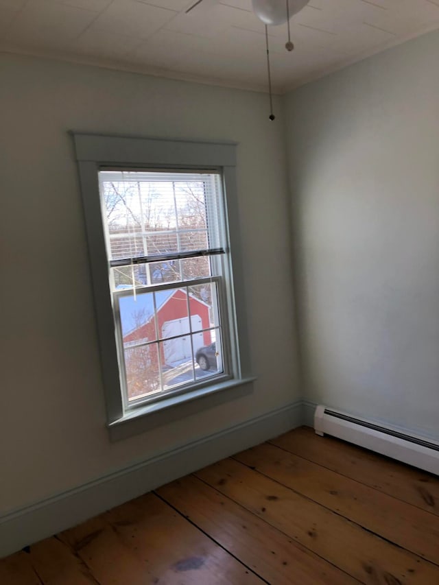 unfurnished room featuring hardwood / wood-style flooring and a baseboard radiator