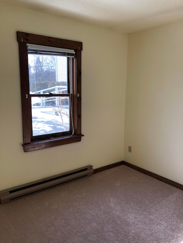 carpeted empty room with a baseboard heating unit