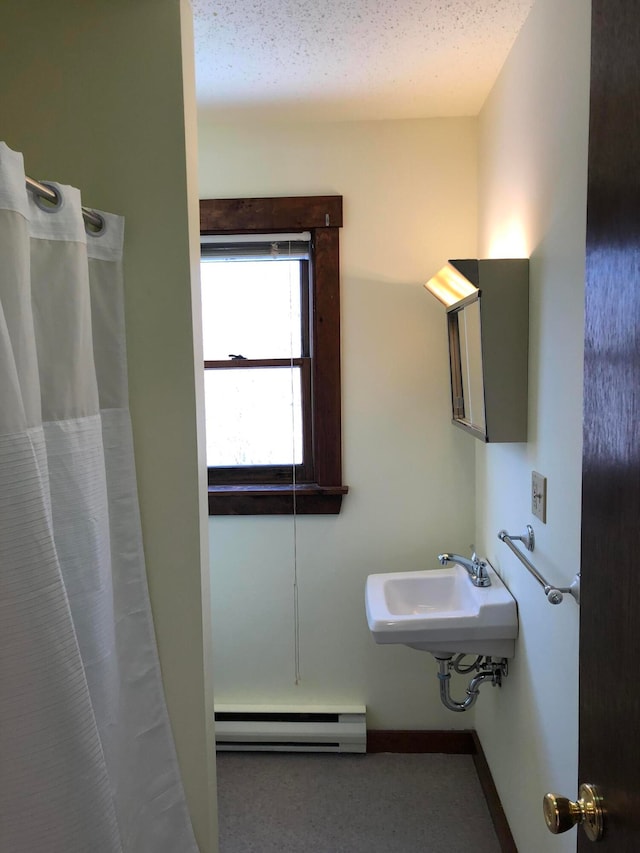 bathroom featuring walk in shower, a textured ceiling, baseboard heating, and sink