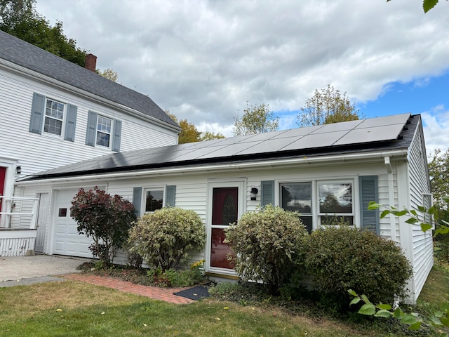 view of front of home with a garage, solar panels, and a front lawn