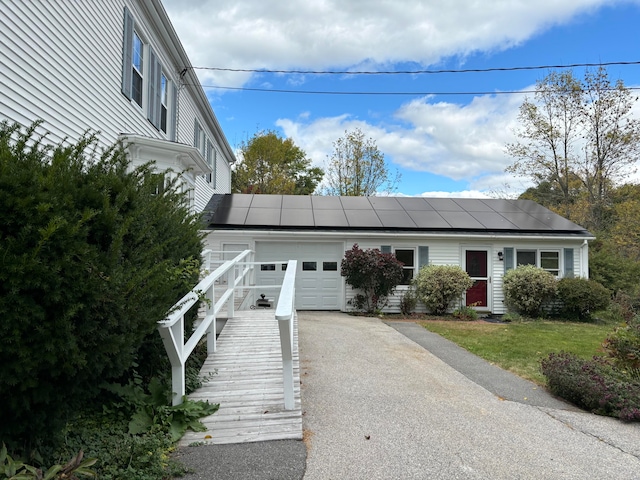 view of front of house featuring a garage, solar panels, and a front lawn